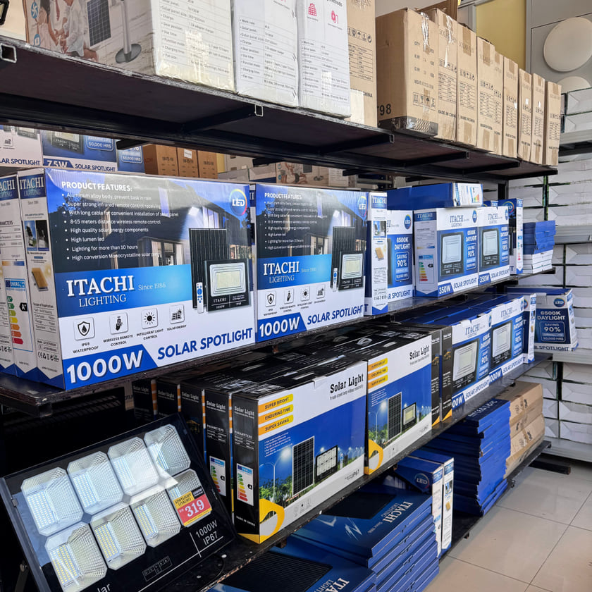 A stock aisle with boxed ITACHI 1000W solar spotlights on the racking.