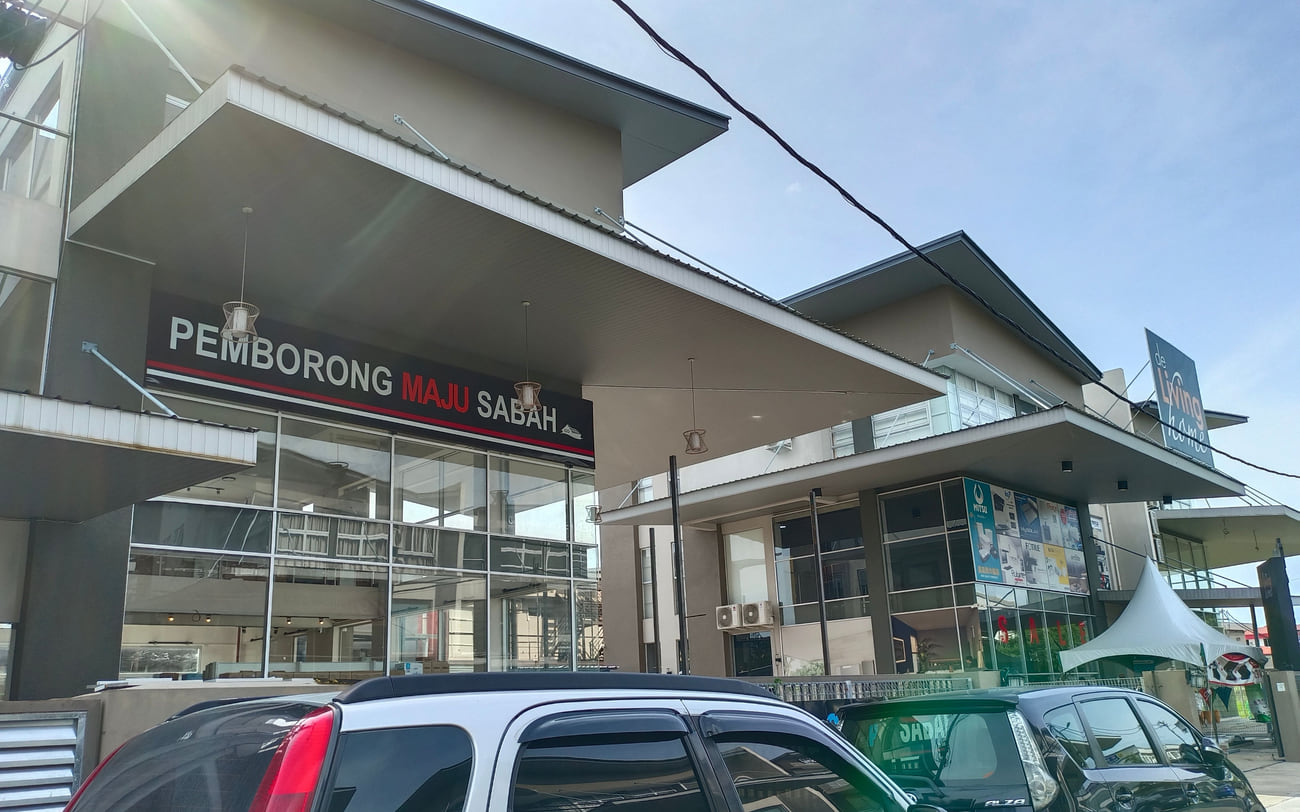 The Inanam premises from the street: a two-storey glazed shop building with cars parked at the frontage.
