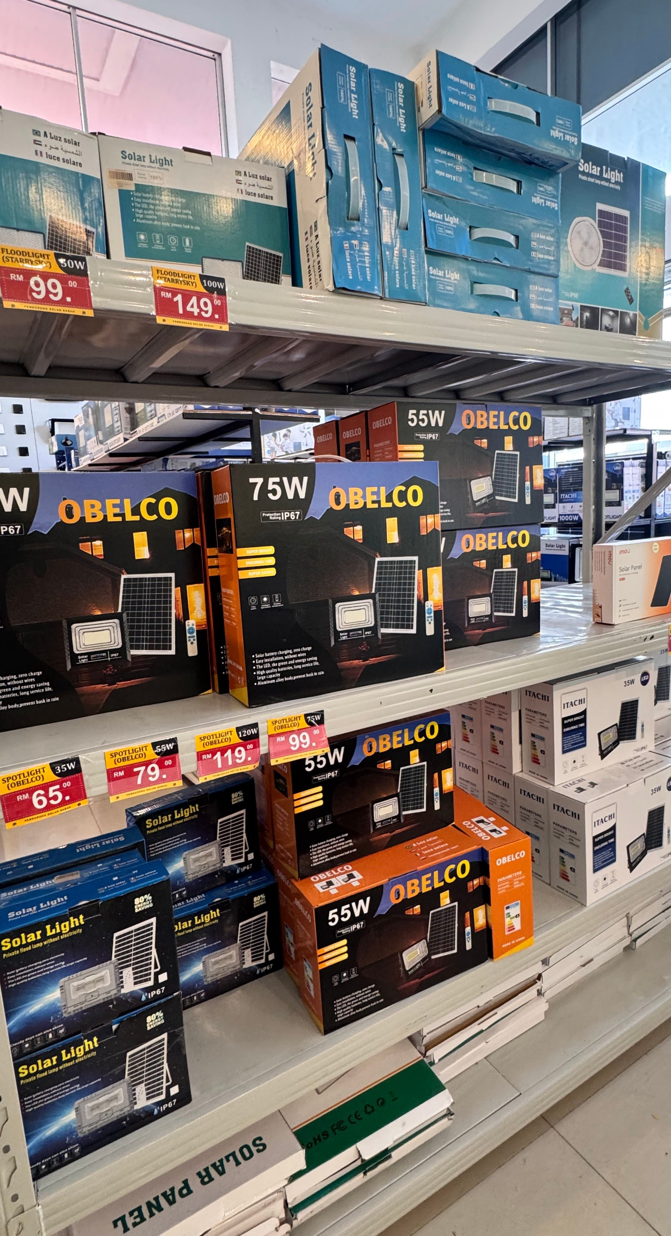 Our racking at Inanam, shelf after shelf of boxed OBELCO solar floodlights and solar lights above the shop cards.