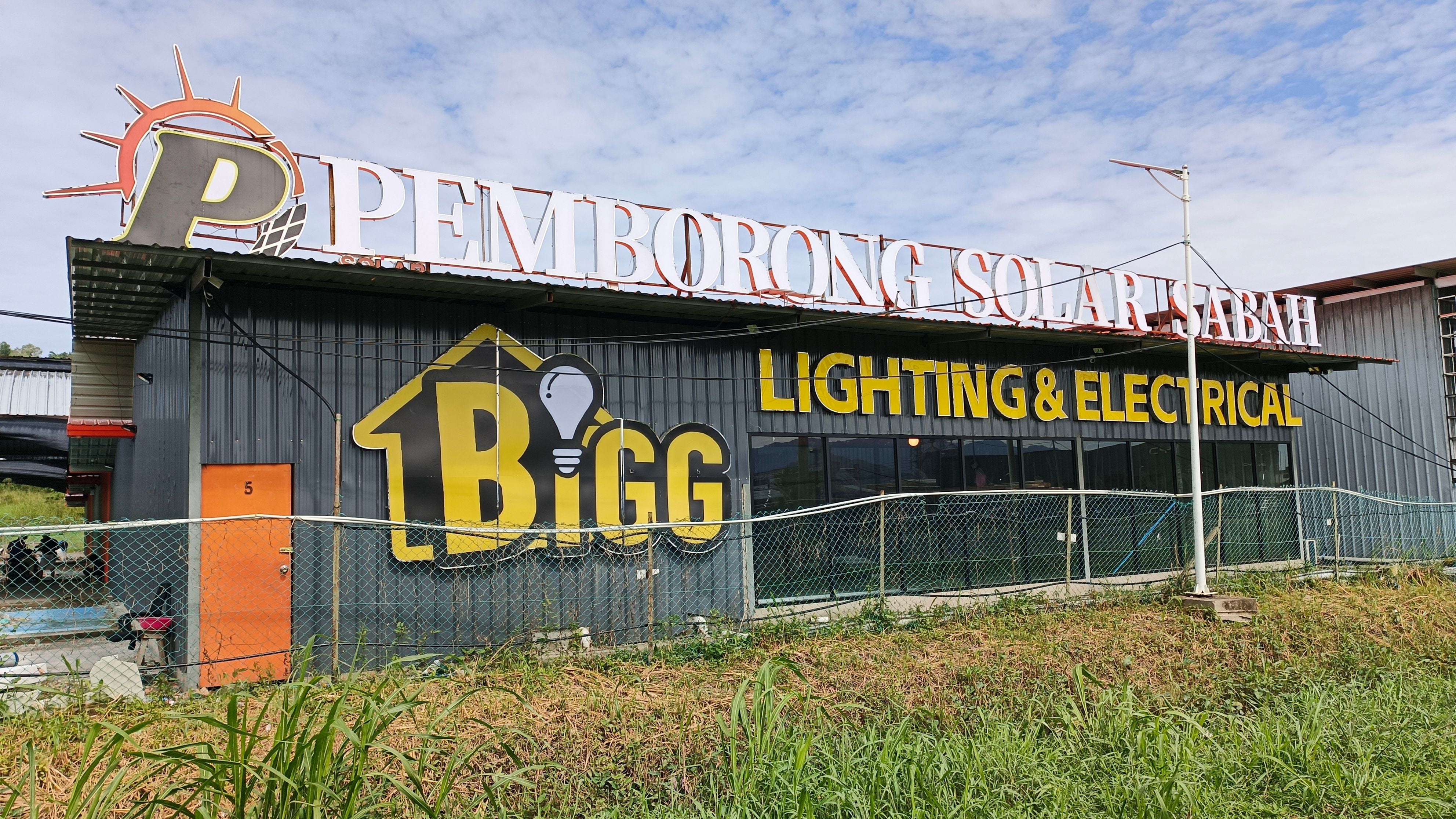 The Kolombong premises: a long grey shed under roofline lettering reading PEMBORONG SOLAR SABAH, with the BiGG Lighting & Electrical panel below it.