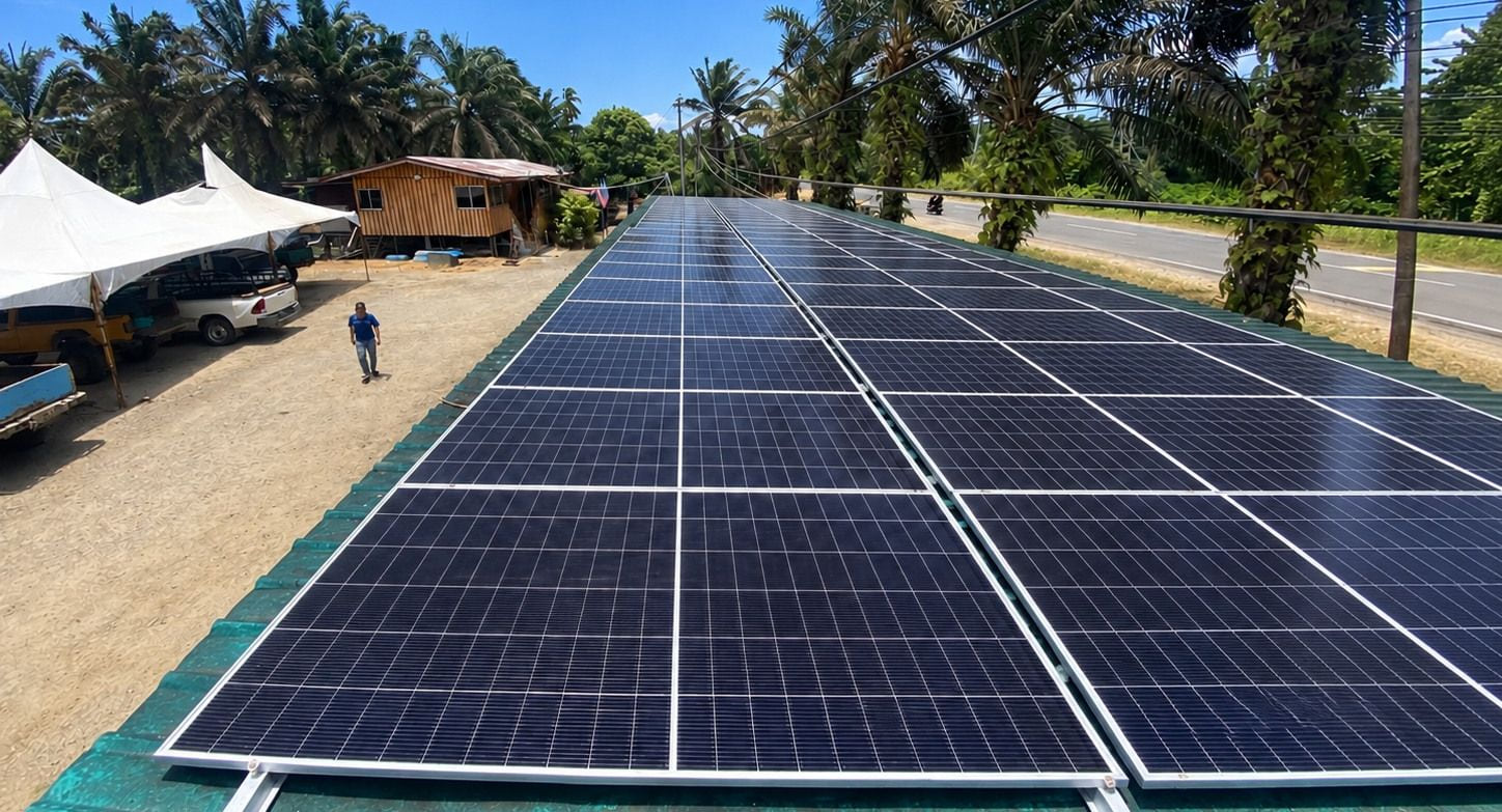 The finished array photographed along its length: two long rows of framed panels on a roof beside a road.