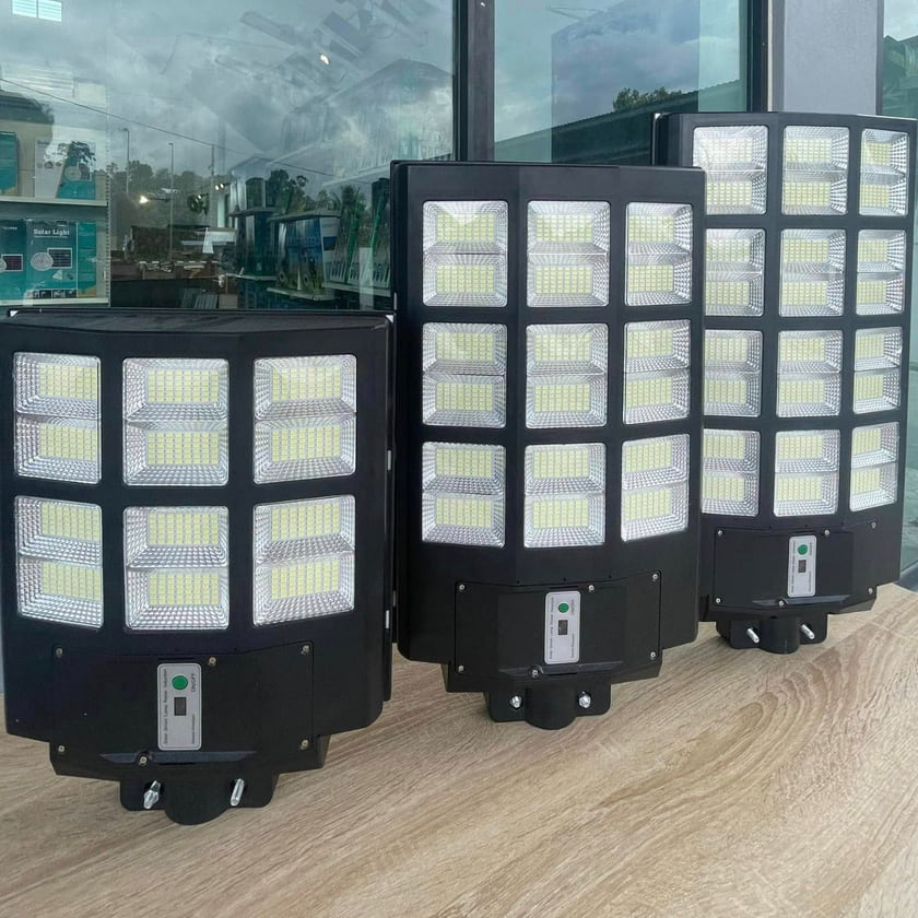 Three all-in-one LED solar street lights of increasing size stood side by side on a table.